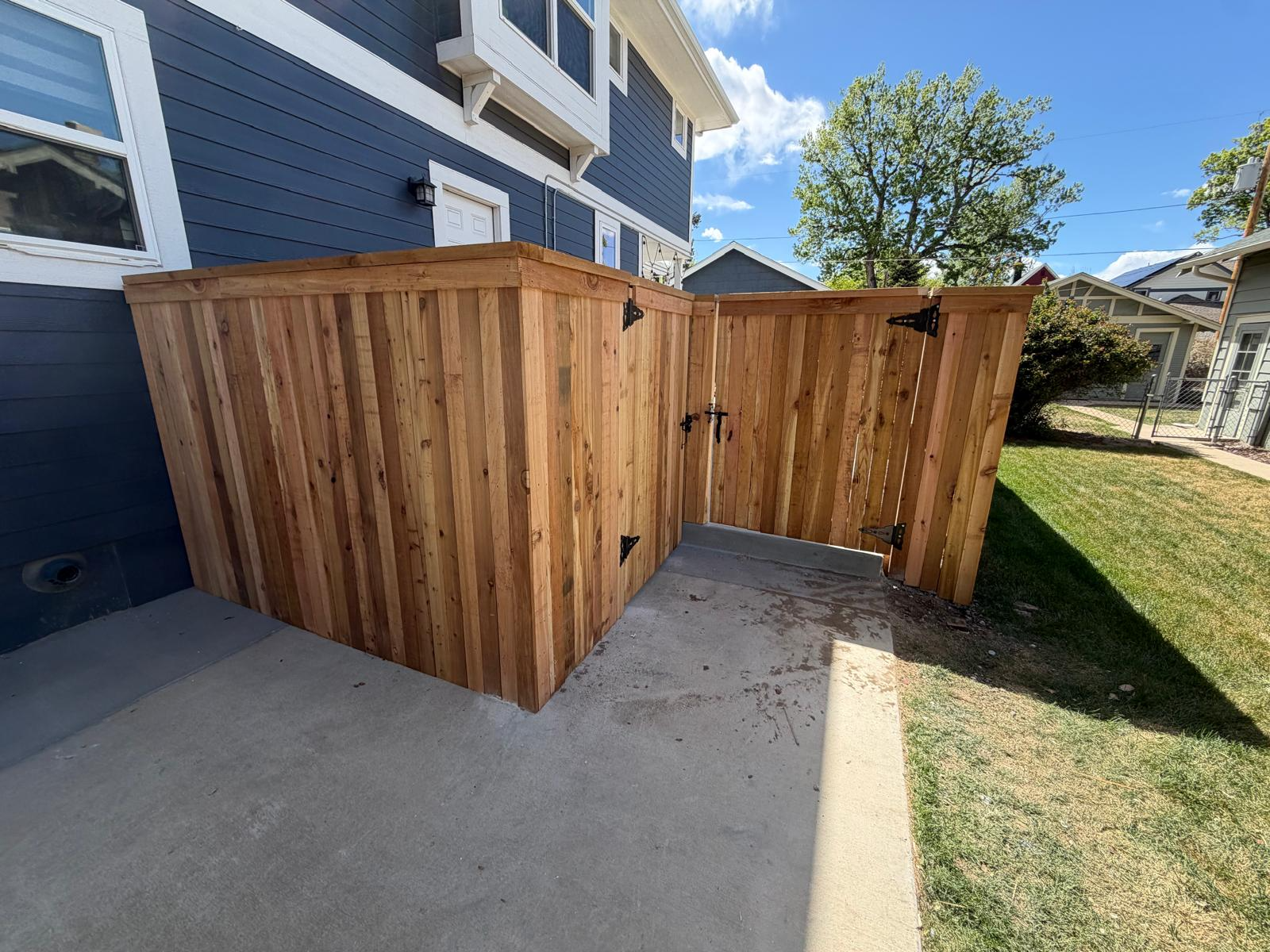Cedar privacy enclosure and gate installation beside a residence